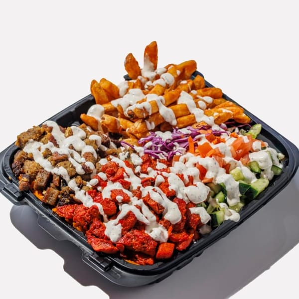 A black takeout container filled with fries, chicken, beef, and salad, all drizzled with white sauce.